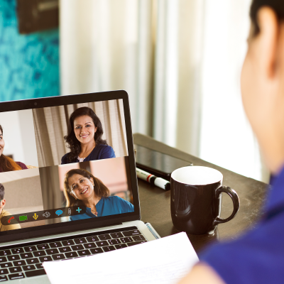 Adult looking at a laptop screen with other smiling adults