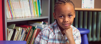 Young boy smiling in front of shelves of books