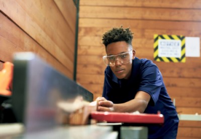 Boy sawing a piece of wood with a circular saw