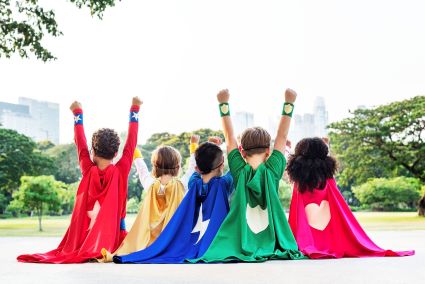 5 students sitting in a row dressed as superheroes